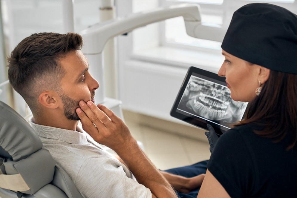 Eine Zahnärztin bespricht das Röntgenbild mit ihrem Patienten.