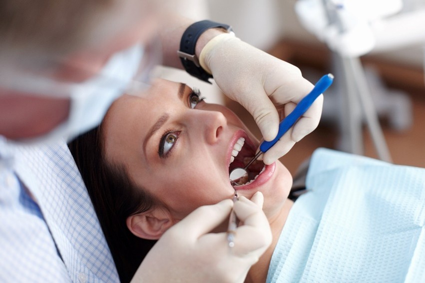 Halitosis Behandlung Ein Zahnarzt kontrolliert den Mundraum seiner Patientin.